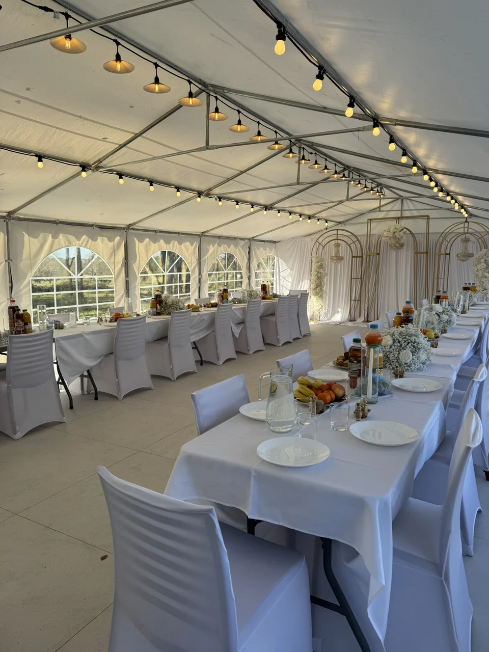 La tente de réception dressée pour un repas, avec tables et guirlandes
